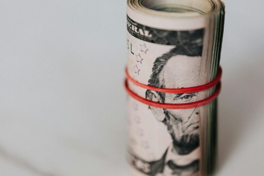 Close-up of a roll of US dollars wrapped with a red rubber band focusing on financial abundance.